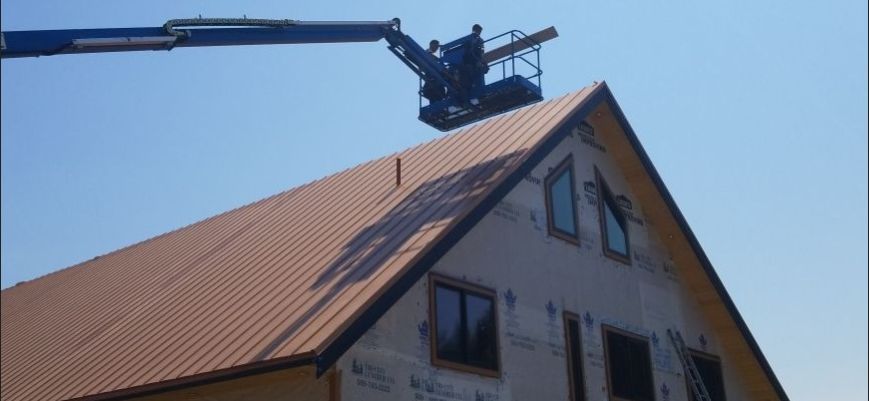 installers in boom lift working on metal roof